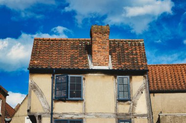 Yarı ahşap duvarlı eski bir Avrupa evi ve bulutlu mavi gökyüzüne karşı kırmızı kiremitli bir çatı. York, North Yorkshire, İngiltere 'de görünür aşınma ve karakter içeren klasik mimari.