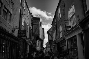 York 'ta, tarihi binalar, antika dükkanlar ve yayaların York, Kuzey Yorkshire, İngiltere' deki büyüleyici eski kasabayı keşfettiği hareketli dar bir caddenin siyah beyaz görüntüsü..