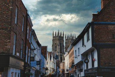Alacakaranlıkta dramatik bir gökyüzünün altındaki görkemli Gotik bir katedrale götüren Avrupa 'nın antika caddesinde York, Kuzey Yorkshire, İngiltere' de tarihi mimari ve şehir cazibesi sergileniyor..