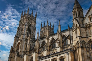 Gotik katedral kulesi dramatik bulutlu gökyüzüne karşı, karmaşık mimari detaylar ve kuleler sergileniyor, York, Kuzey Yorkshire, İngiltere 'deki tarihi veya dini temalar için ideal..