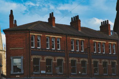 Birden fazla bacası olan geleneksel kırmızı tuğla bina açık bulutlu mavi gökyüzüne karşı, York, Kuzey Yorkshire, İngiltere 'de klasik şehir mimarisini sergiliyor..