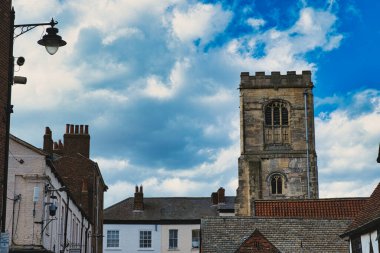 Tarihi binaları ve çarpıcı bir gökyüzünün altında York, Kuzey Yorkshire, İngiltere 'de kabarık bulutları olan önemli bir kilise kulesi olan antika Avrupa caddesi..