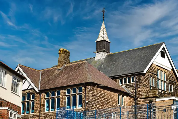 Traditional brick school building with a spire against a blue sky with wispy clouds in Harrogate, North Yorkshire.