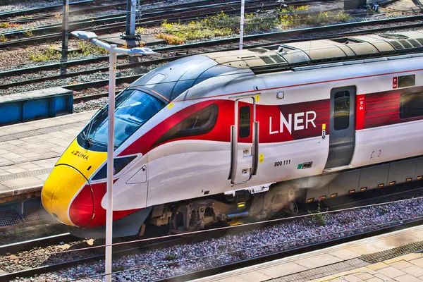 İstasyonda modern bir LNER treni, parlak tasarımı ve canlı renkleri sergiliyor.