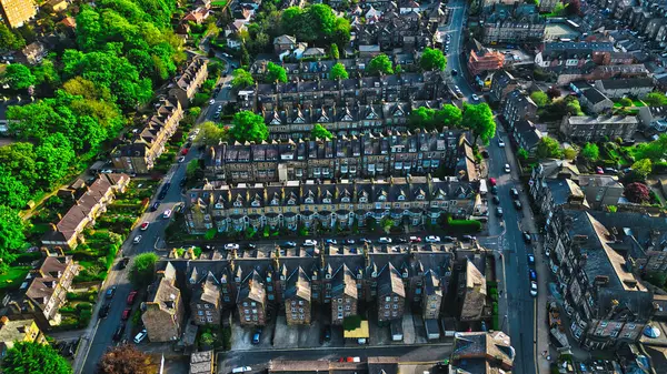 stock image Aerial view of a residential neighborhood with rows of houses, trees, and streets. The houses have similar architectural styles and are closely packed together. The area is surrounded by greenery and appears to be in an urban setting.