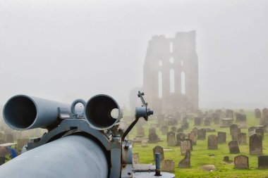 A foggy scene of an old cemetery with a large cannon in the foreground and the ruins of a stone building in the background. clipart
