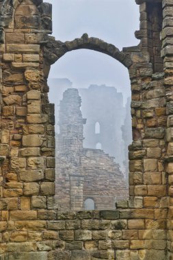 A view through a stone archway of ancient ruins with mist in the background. clipart