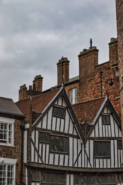 A historic half-timbered building with brick chimneys and a cloudy sky. clipart