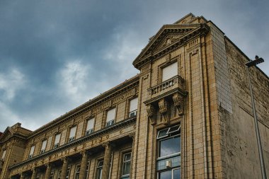 Dekoratif sütunlar ve kasvetli bir gökyüzüne karşı belirgin bir korna içeren karmaşık mimari detaylarla süslü tarihi bir binanın yakın görüntüsü..