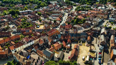 Konut ve ticari binaların karışımından oluşan tuhaf bir kasabanın havadan görünüşü. Çatılar, çeşitli mimari tarzlarla ağırlıklı olarak kırmızıdır. Sokaklar park halindeki arabalar ve yeşilliklerle kaplı. Resimli bir şehir manzarası yaratıyorlar..