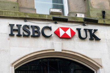 HSBC banka şubesinin dış tabelaları, HSBC logosu ve 'UK' sözcüğünün yer aldığı. İşaret, arka planda tarafsız bir bina cephesi bulunan bir girişin üzerinde belirgin bir şekilde gösteriliyor..