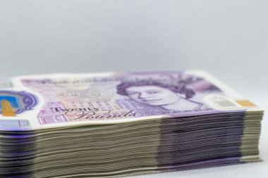 20 poundluk banknotların yakın plan görüntüsü, paranın karmaşık ayrıntılarını ve renklerini gözler önüne seriyor. Notlar düzgünce düzenlenmiş, önünde Kraliçe II. Elizabeth 'in portresi var..