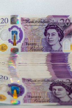 Kraliçe 2. Elizabeth 'in portresinin ve holografik güvenlik özelliklerinin yer aldığı üst nota odaklı 20 poundluk İngiliz banknotlarının yakın çekimi..