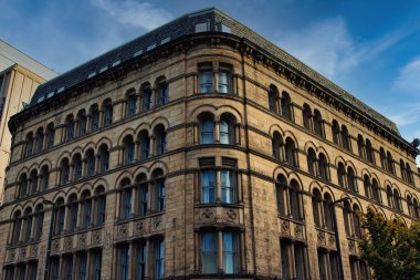 Manchester, İngiltere 'de kemerli camları ve dekorasyonu olan eski bir taş binanın düşük açılı görüntüsü..