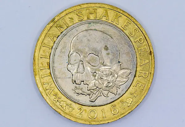 Yakından bakınca, içinde William Shakespeare 'in adı, bir kafatası ve bir gülün bulunduğu 2016 İngiliz hatıra parası görülüyor. Altın ve gümüş bimetalik..