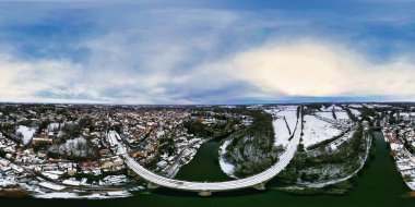 Nehir kenarındaki karla kaplı bir kasabanın havadan panoramik görüntüsü, kıvrımlı bir karayolu köprüsü ve demiryolu hattı içeriyor. İngiltere, Knaresborough 'da gökyüzü parçalı bulutludur..