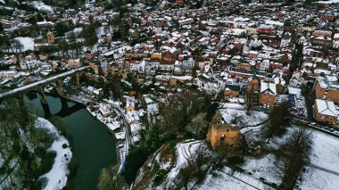 Nehir, taştan viyadük ve kale kalıntıları olan karla kaplı bir kasabanın havadan görünüşü. Binalar yoğun bir şekilde tıka basa doludur ve mimari tarzların bir karışımını sergiler. Sahne, İngiltere 'nin Knaresborough kentindeki sessiz kış renklerinin egemenliğinde..
