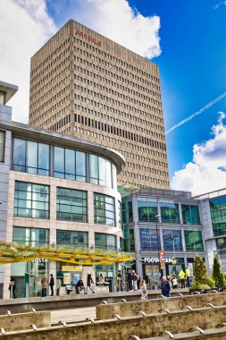 Uzun, bej bir ofis binası olan ArnDale 'in yer aldığı şehir manzarası, modern cam önlü ticari binalar ve yayalar tarafından kısmen gizleniyor. Sarı bir kubbe Manchester, İngiltere 'de bir Costa Kafe' yi kapsıyor..