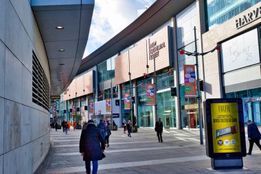 Modern mimari, sayısız mağaza önü, yayalar ve reklam vitrinleri olan güneşli bir şehir geçidi. Yeni Katedral Pazarı, İngiltere 'nin Manchester şehrinde yer almaktadır..