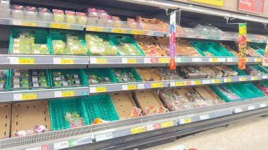 Çeşitli üzüm çeşitlerini gösteren ve plastik kaplar ve karton kutularda meyve bardakları hazırlayan soğutmalı bir markette. Raflar kısmen boş..
