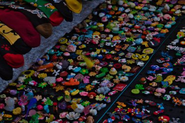 Renkli çoraplar ve çeşitli tılsımlar, muhtemelen İngiltere, York 'ta bir pazarda ya da fuarda satılmak üzere karanlık bir yüzeye serilmiştir..