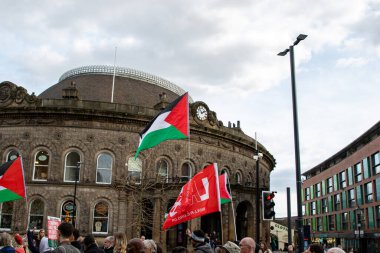 Bulutlu bir gökyüzünün altındaki Corn Exchange binasının önünde bayraklı bir kalabalığın açık hava görüntüsü..