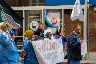 İnsanlar yürüyor, ellerinde işaretler ve bayraklar var. İşaretler diyor ki: 