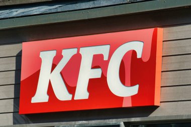 Manchester, İngiltere 'de gri kaplamalı ve koyu kenarlı bir binaya bağlı kırmızı beyaz bir KFC tabelasının yakın çekimi..