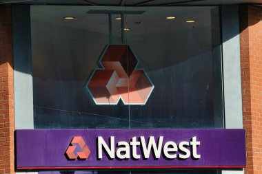 Logosu ve tabelaları belirgin bir şekilde sergilenen bir NatWest banka şubesinin dış görünüşü. Manchester, İngiltere 'de inşaat malzemeleri ve pencere görünür..