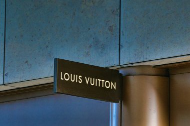 Manchester, İngiltere 'de aydınlatılmış harflerle dokulu bir duvara monte edilmiş Louis Vuitton tabelasının yakın çekimi..