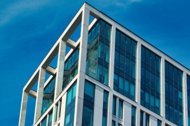 Camdan pencereleri ve Manchester, İngiltere 'de açık mavi gökyüzüne karşı açık renkli çerçevesi olan modern bir ofis binasının alçak açılı görüntüsü..