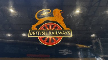 İngiliz Demiryolları ambleminin yakın çekimi: kırmızı tekerleğin üzerinde yazılı altın bir aslan. Ulusal Demiryolu Müzesi York 'ta donanmanın arka planında ışık yansımaları var.