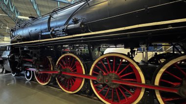 Büyük kırmızı ve beyaz tekerlekleri olan siyah bir buhar treninin yakın çekimi. Trenin mekanizmasının ayrıntıları York Ulusal Demiryolu Müzesi 'nde görülüyor..