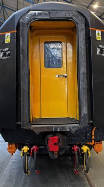 Ulusal Demiryolu Müzesi York 'ta görünür bağlantı noktaları ve uyarı levhalarıyla parlak sarı bir kapısı olan bir tren vagonunun sonuna yakın çekim..