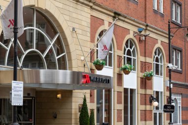 Marriott Otel 'in dış görünüşü tuğla cephe, kemerli pencereler, bayraklar ve Leeds, İngiltere' de bir tabela içeriyor..