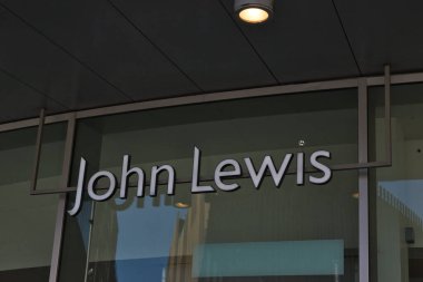 John Lewis mağaza önü tabelasının yakın çekimi. Siyah çizgili beyaz harfler, Liverpool, İngiltere 'de üst üste asılmış bir tavanın altında metal çerçeveli cam bir cepheye monte edilmiştir..
