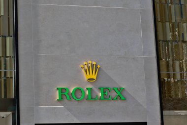 Gri fayans duvarında Rolex logosu, yanında da modern cam ve altın aksanlı. Liverpool, İngiltere 'de doğal ışık gölgeleri oluşturdu.