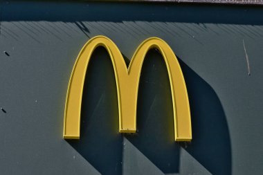 Sarı bir McDonald 's M logosuna yakın plan koyu yeşil arka planda Liverpool, İngiltere' de gölgeler var..