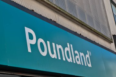 Beyaz harfli, deniz mavisi poundland tabelanın alçak açılı görüntüsü. Kuş çivileri en üstte. Liverpool, İngiltere 'de dış bina ağ ve betonla kaplı..
