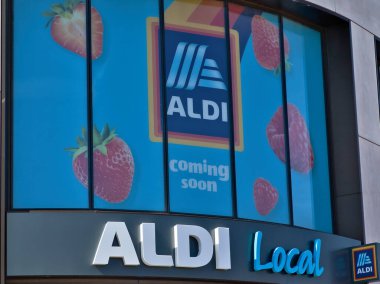 Bir Aldi Yerel Dükkanı 'nın dış görünüşü. Pencereler Aldi logosunu, meyve resimlerini ve 