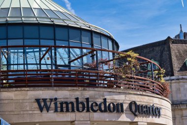 Wimbledon Quarter binasının dış görüntüsü, cam kubbe, sicim lambalı balkon, ve tabelalı taş cephe.