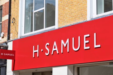 H. Samuel mağaza tabelasının yakın çekimi, kırmızı arka plan ve beyaz harfler içeriyor. Binanın tuğla cephesi Kingston, İngiltere 'de görülebiliyor..
