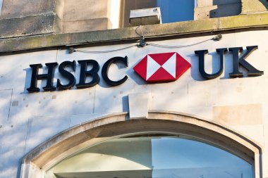 Harrogate, Yorkshire, İngiltere 'deki bir kemerli pencerenin üzerinde siyah harflerle kırmızı-beyaz logo bulunan bir binanın ön cephesinde HSBC UK tabelasının yakın çekimi..