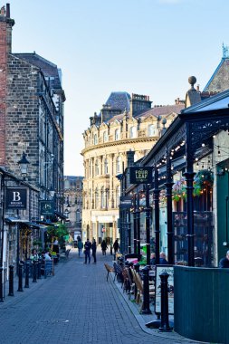 Tuğla binalar, açık kafeler, yürüyen insanlar Harrogate, Yorkshire, İngiltere 'de açık bir gökyüzü altında sicim ışıkları..