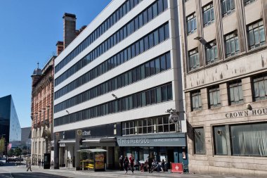 Parlak bir gökyüzü altında tarihi binaların yanında modern bir binayla karışık mimari sokak manzarası. İngiltere, Liverpool 'da kaldırımda insanlar var..