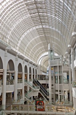 Geniş kemerli cam tavanı, yürüyen merdivenleri ve cam asansörü olan çok katlı bir alışveriş merkezinin iç manzarası. Kingston, İngiltere 'deki Bentall Center' da ağırlıklı olarak beyaz ve parlak..