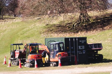 İngiltere 'nin Studley Royal Park kentindeki çıplak ağaçların yakınındaki çimenli bir arazide kazı araçları, karavan ve nakliye konteynırı da dahil olmak üzere inşaat ekipmanları park halindedir..