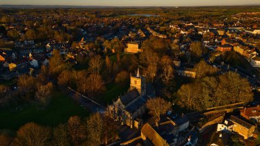 İngiltere 'nin Knaresborough şehrinde altın saat boyunca önemli bir kilise, evler, ağaçlar ve göl manzaralı bir yer..