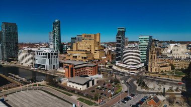 Açık mavi gökyüzü altındaki bir şehrin hava manzarası modern binalar ve tarihi bir kilise ile Liverpool, İngiltere 'de görülebilir bir kanal ve park alanlarına sahiptir..
