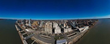 İngiltere, Liverpool 'un panoramik hava görüntüsü, açık mavi gökyüzü altında şehrin ufuk çizgisini, rıhtımı ve Mersey Nehri' ni gösteriyor..